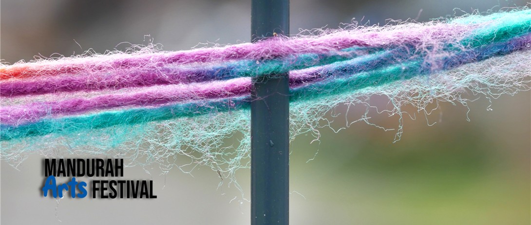 Lengths of purple and blue yarn are stretched across a metal fence line